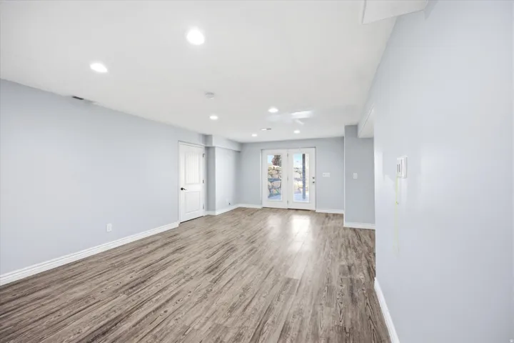 Spacious room featuring wood-finish flooring, recessed lighting, and light-toned wall paint