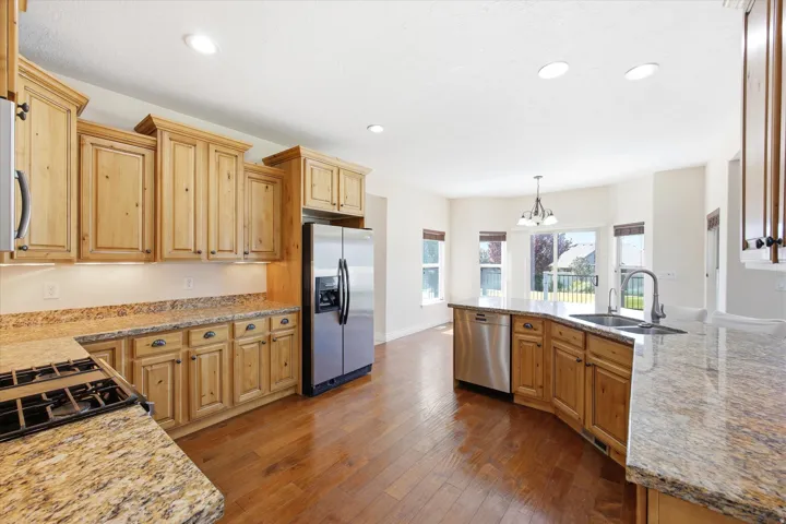 Kitchen featuring wood-finish cabinetry, stainless steel appliances, granite countertops, a gas range, and a built-in kitchen island with a double basin sink