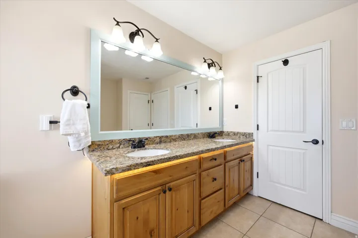 Dual vanity with a speckled countertop, integrated sinks, and natural wood cabinetry
