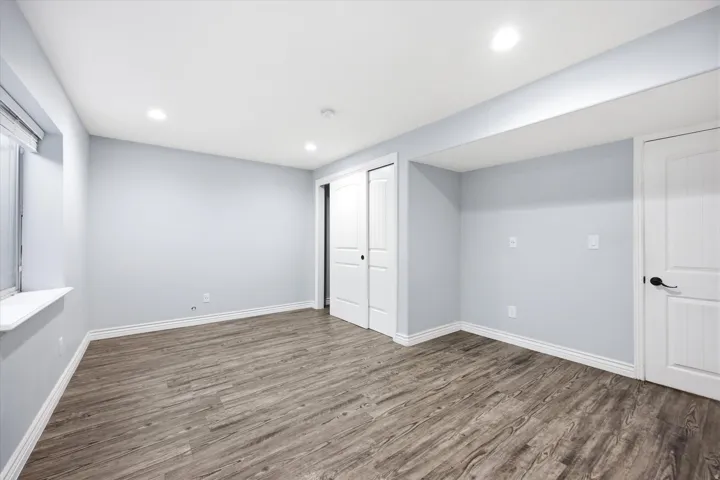 Spacious room featuring wood-finish flooring, recessed lighting, and a window with a white sill