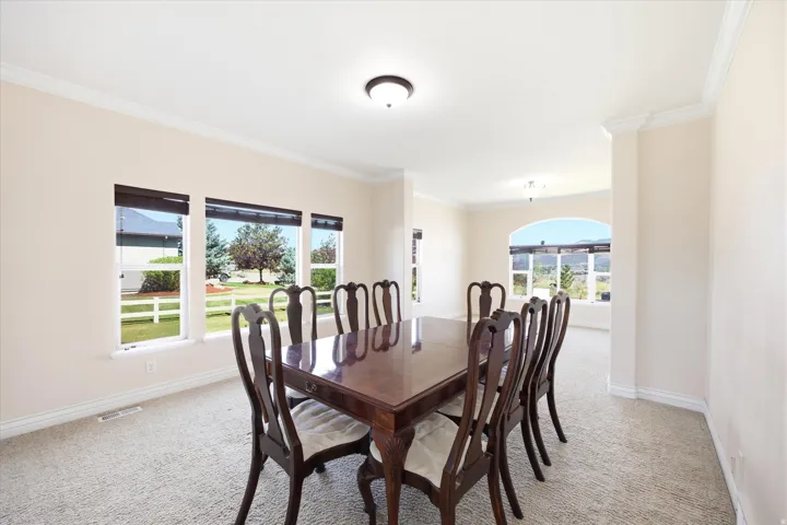 Formal dining space featuring light-toned walls, crown molding, and plush carpeting