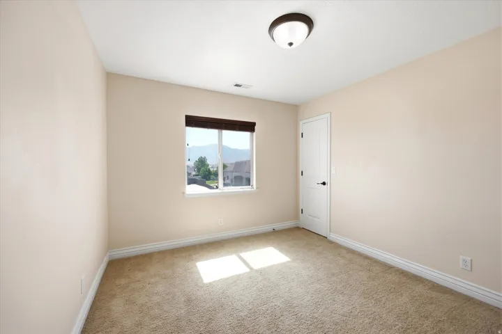 Neutral-toned room featuring light beige walls and a window with dark wood-finish blinds