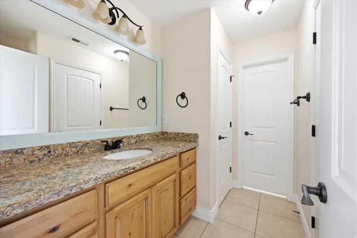 Bathroom vanity featuring a light wood-finish cabinet, a speckled countertop, and an undermount sink with a dark-finish faucet