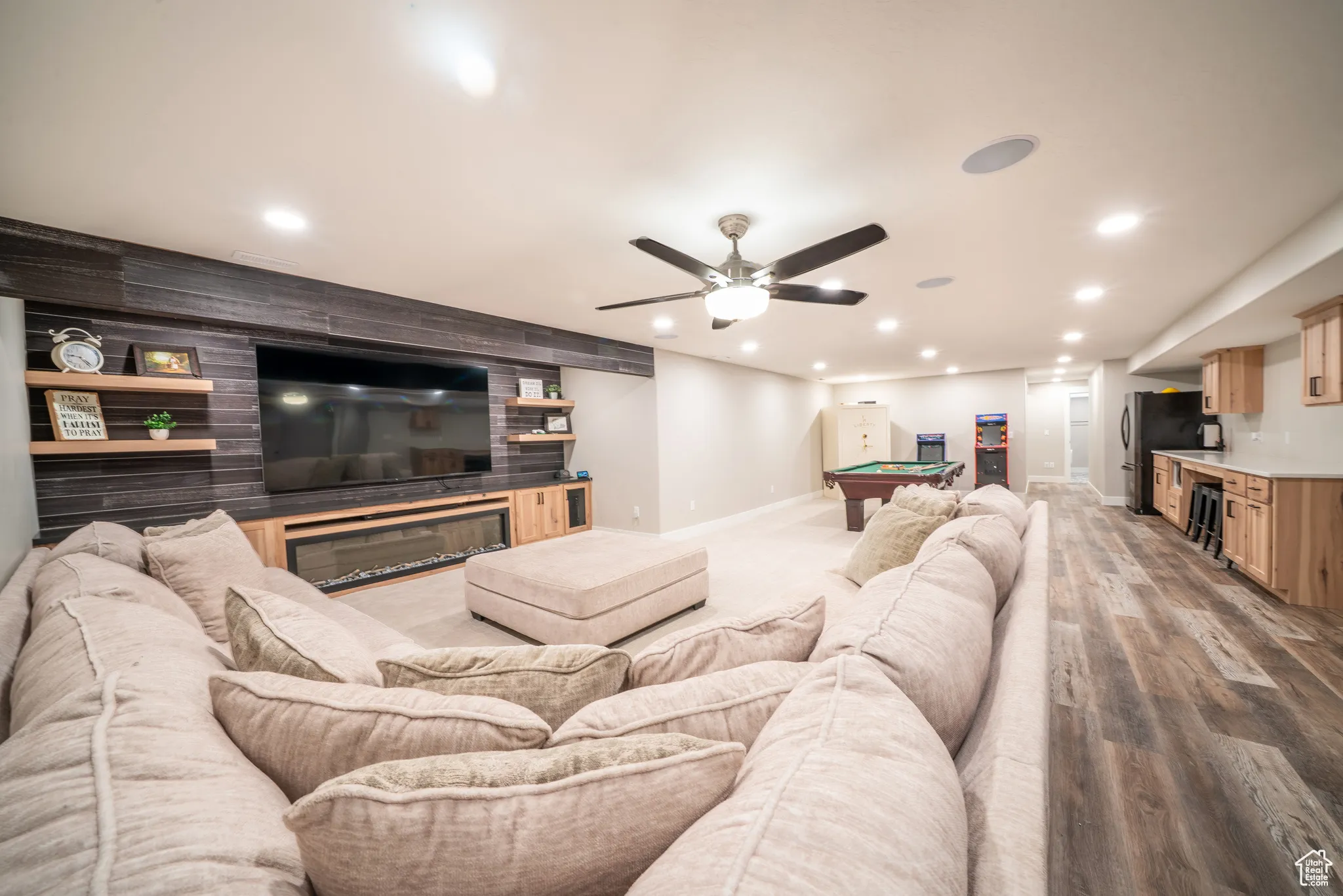 Entertainment space in basement featuring a linear fireplace with wood-finish surround, recessed lighting, ceiling fan, and wood-finish flooring
