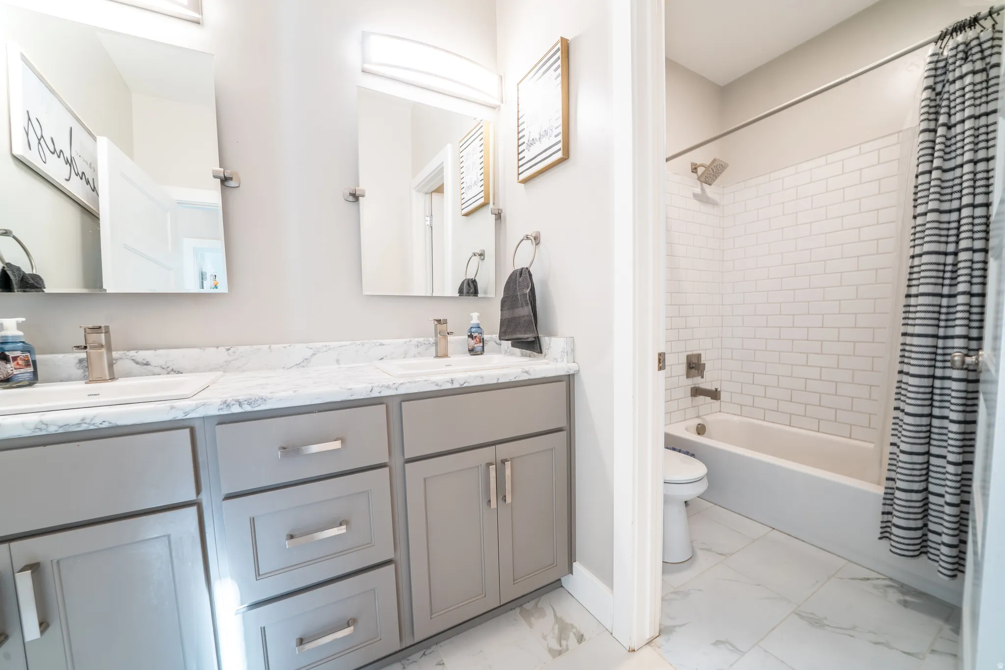 Bathroom featuring a double vanity with gray cabinetry, white countertops, and dual rectangular sinks with brushed nickel fixtures