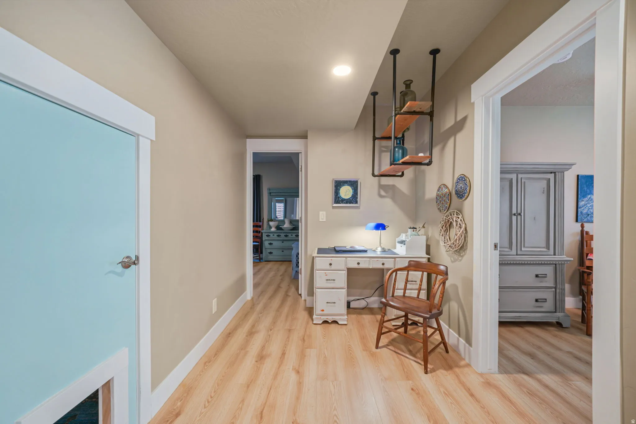 Hallway featuring wood-finish flooring, light beige walls, and white trim