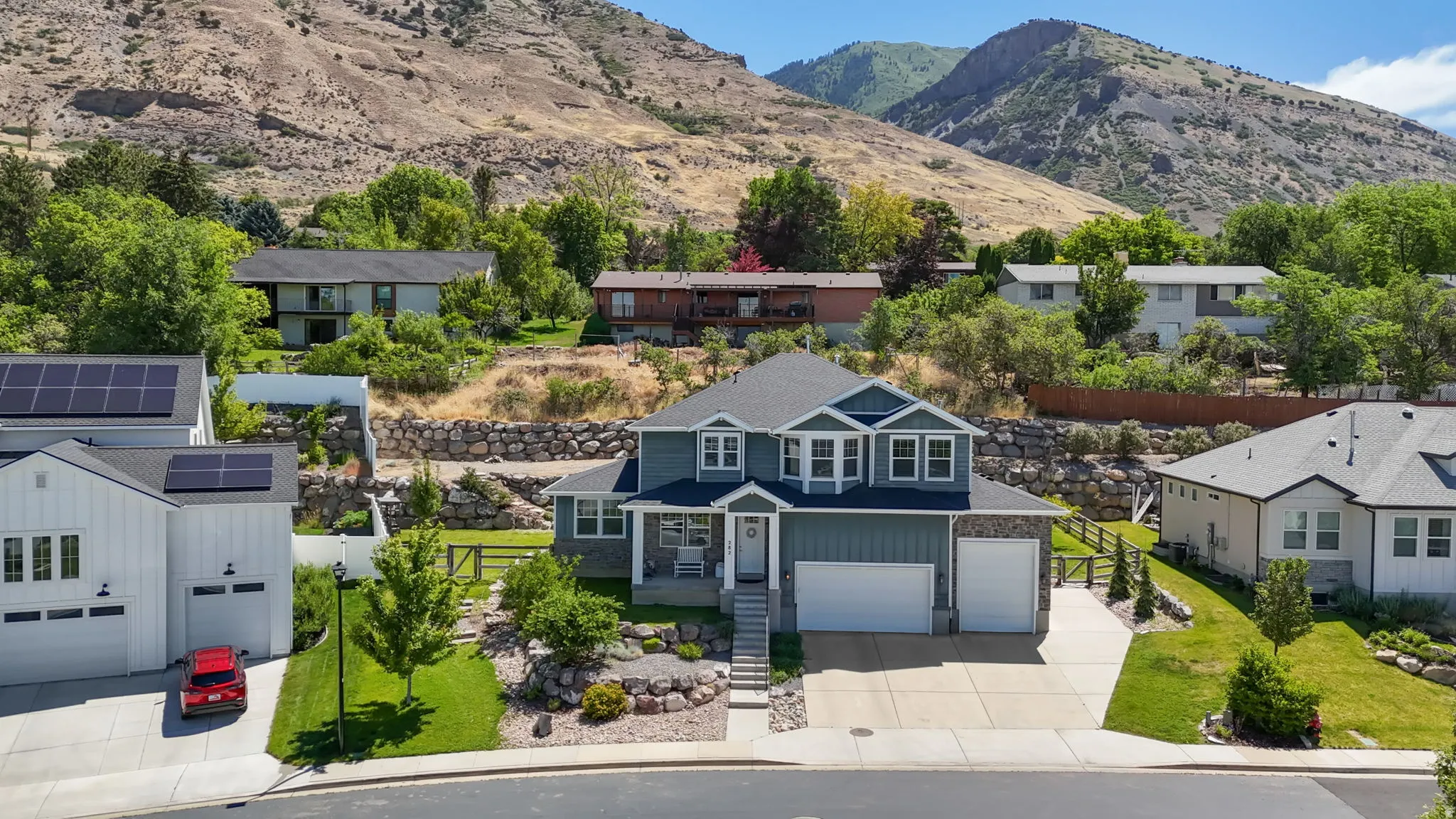 Two-story residence featuring light blue siding with stone accents, a multi-gabled roofline, and a two-car garage