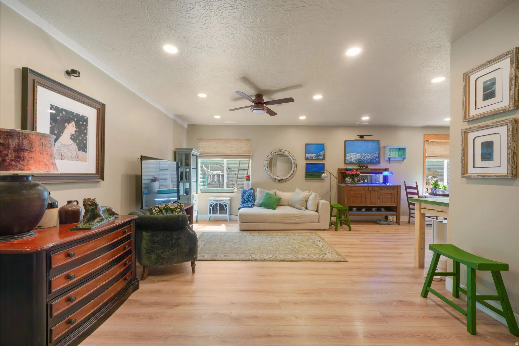 Spacious open-concept room featuring light wood-finish flooring, recessed ceiling lighting, a ceiling fan, and crown molding