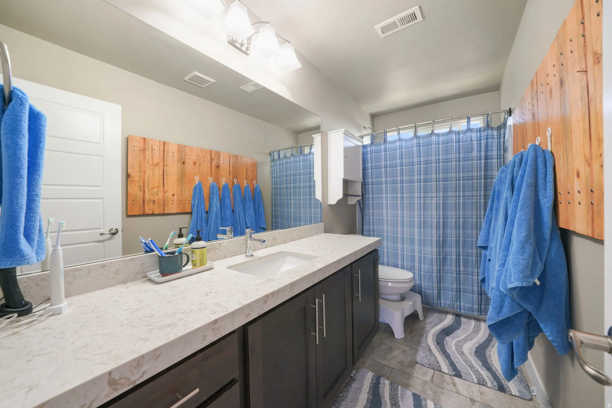 Bathroom featuring an extended vanity with a light-toned countertop, a single undermount sink, and dark wood-finish cabinetry