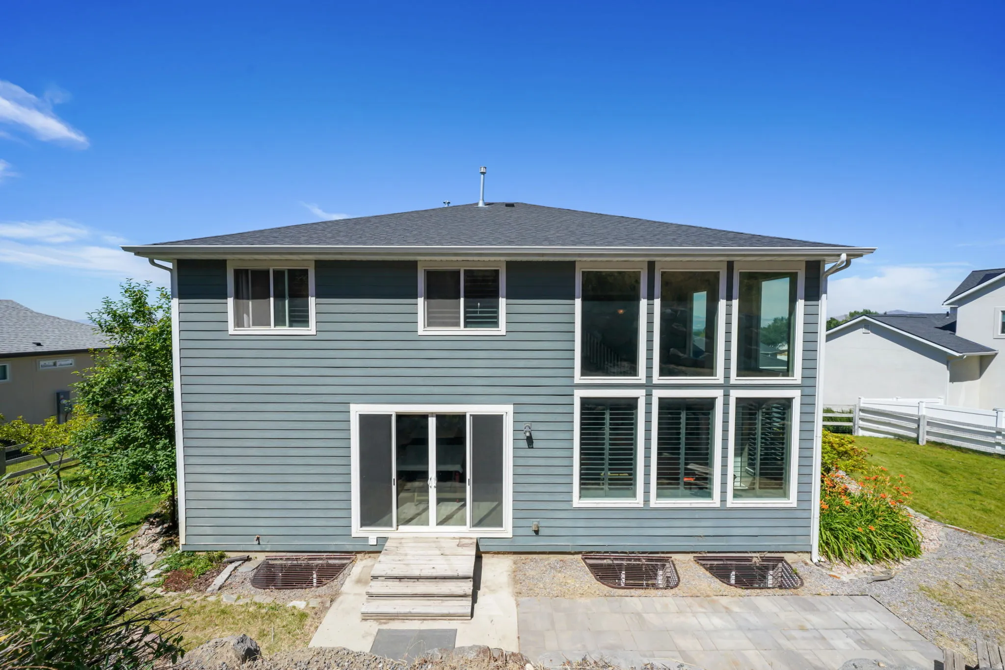 Rear exterior featuring multi-level siding, a shingled roof, and a large window array