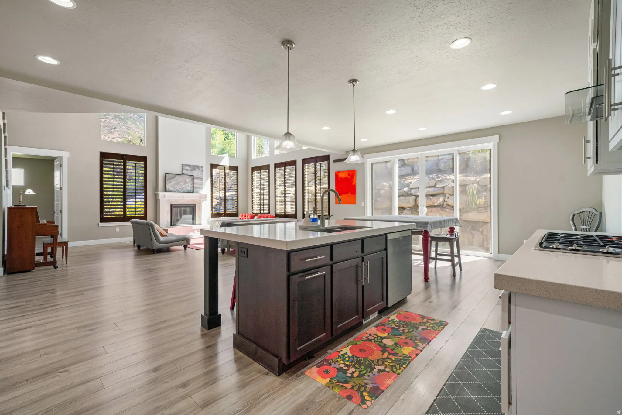 Open-concept living area featuring wood-finish flooring, a central kitchen island with dark cabinetry and light countertops, and recessed lighting
