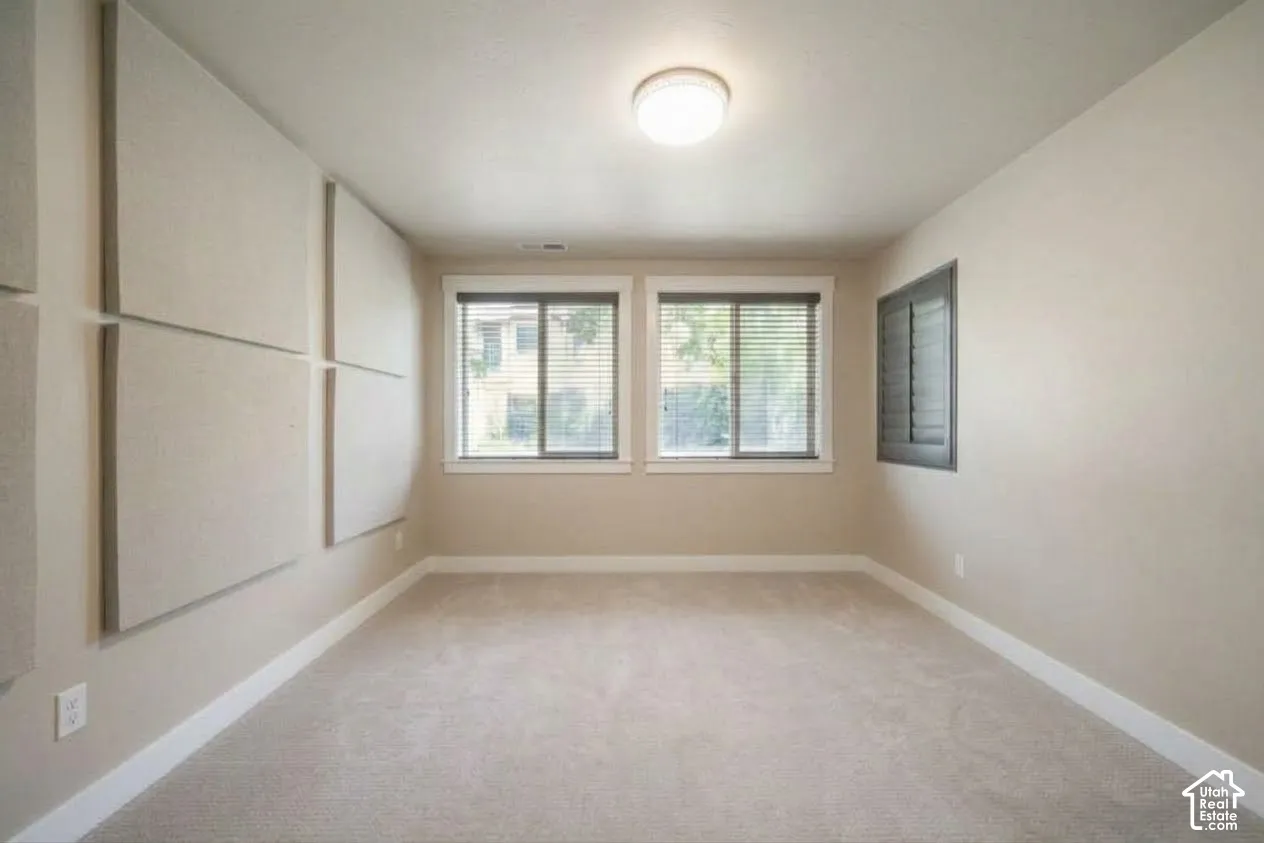 Neutral wall finish, sound-dampening wall panels, light-toned carpeting, two windows with blinds, and recessed lighting