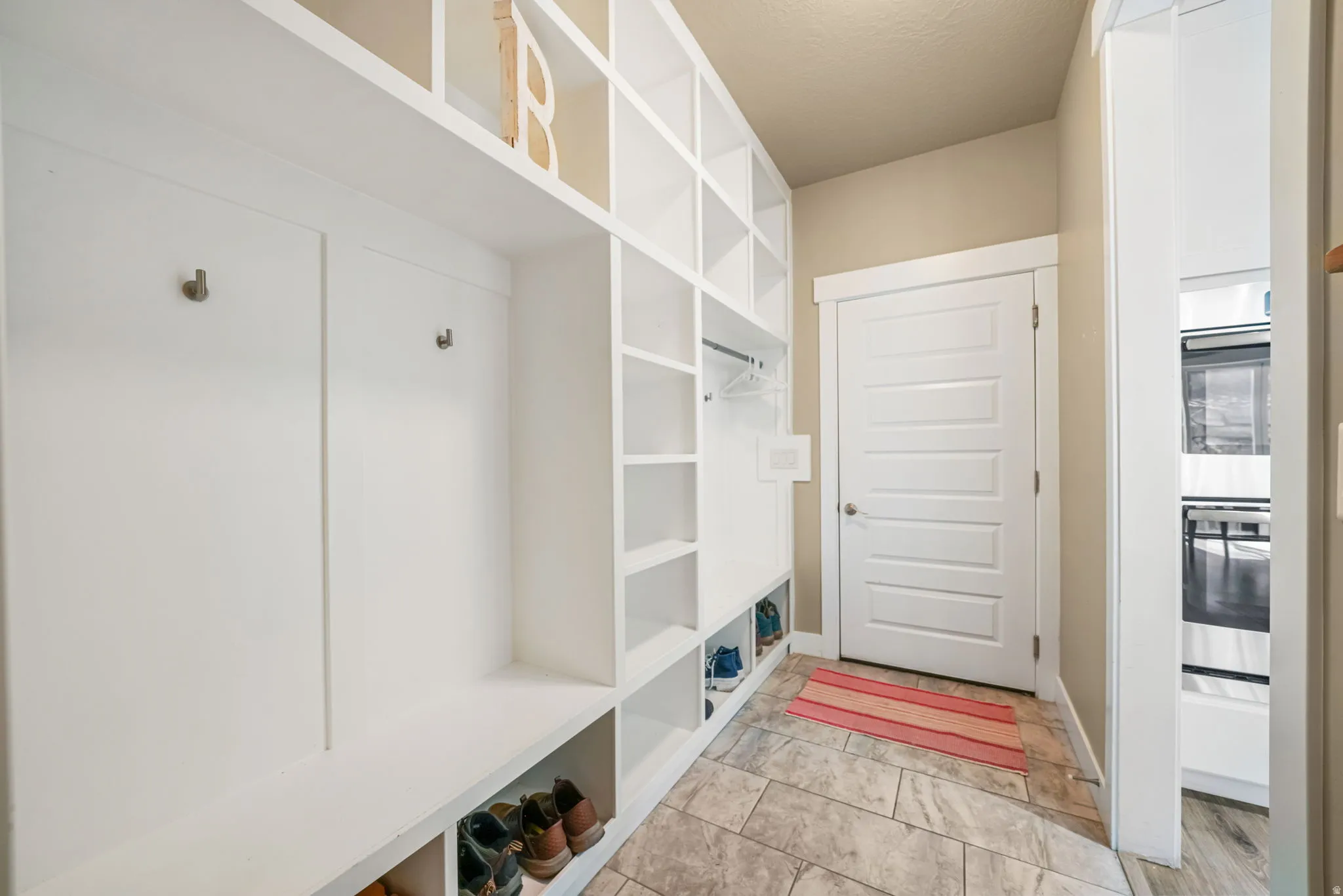 Built-in white cabinetry and shelving system featuring individual cubbies and coat hooks