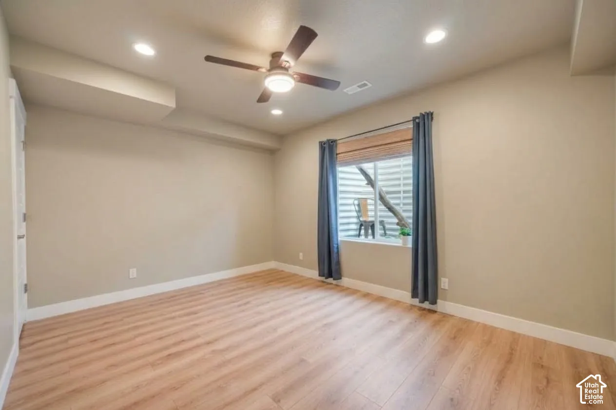 Wood-finish flooring, recessed lighting, ceiling fan, neutral wall paint, and white trim
