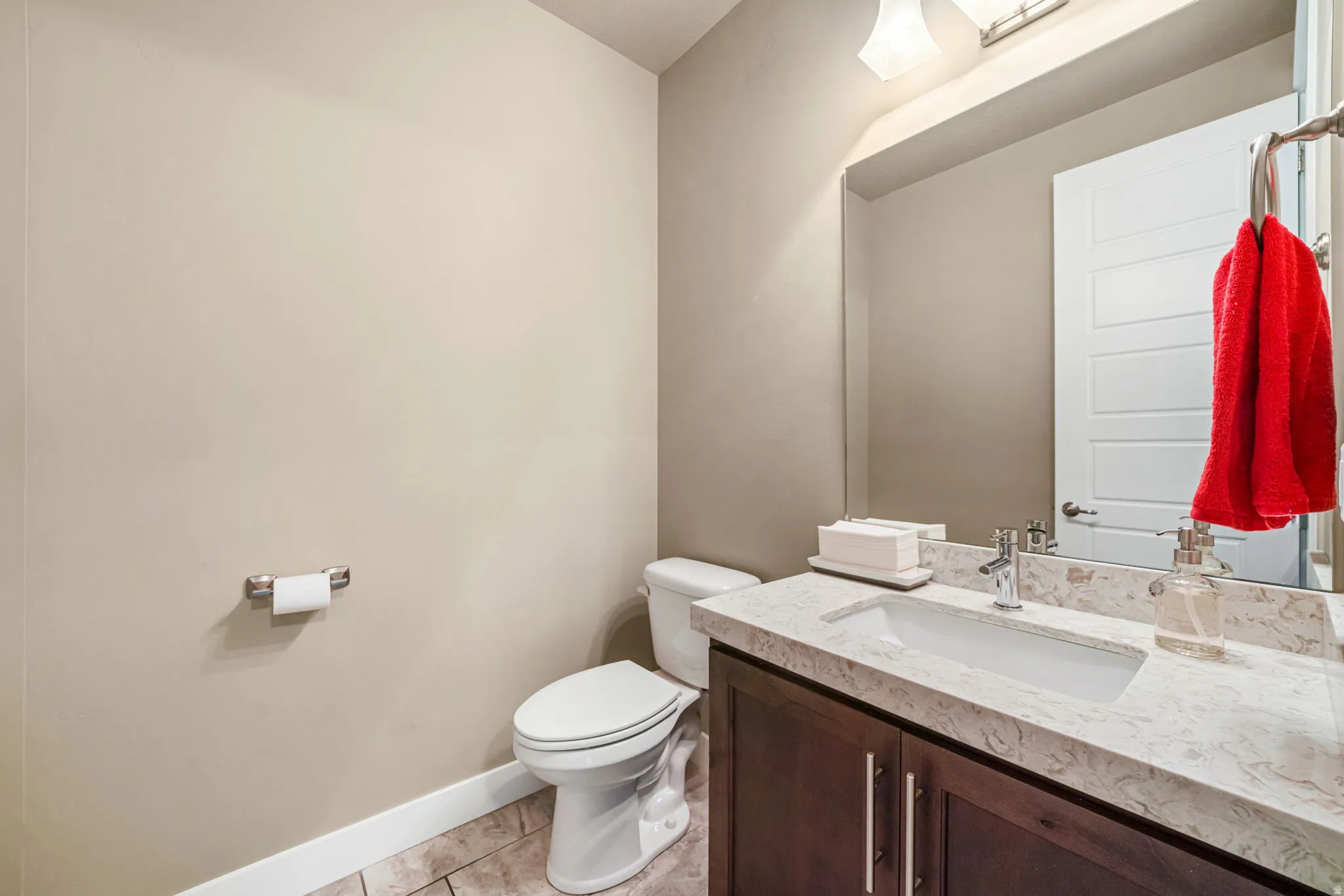 Powder room featuring a single vanity with a light-toned countertop, a built-in rectangular sink, and a chrome faucet
