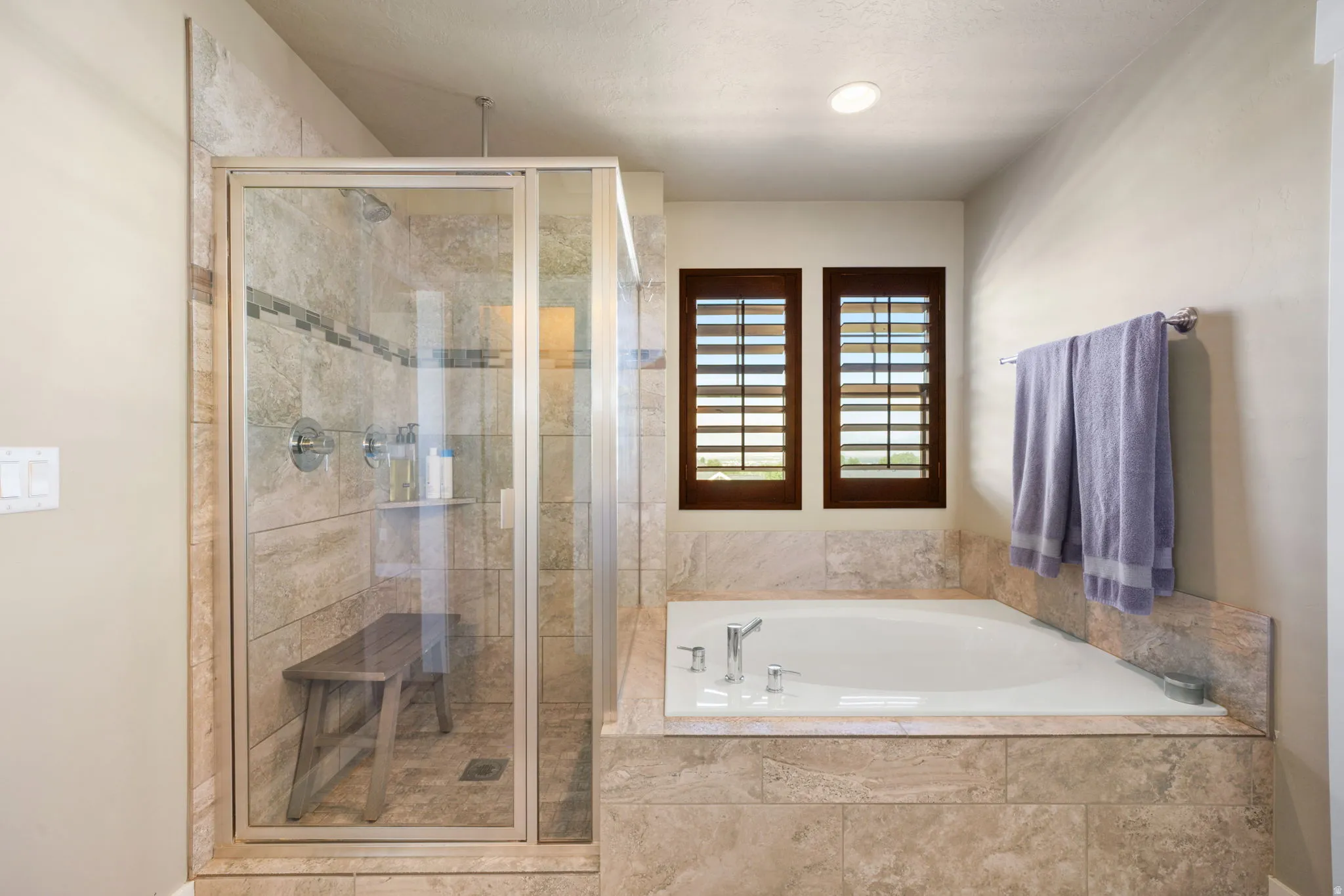 Walk-in shower with clear glass enclosure and stone-tiled walls