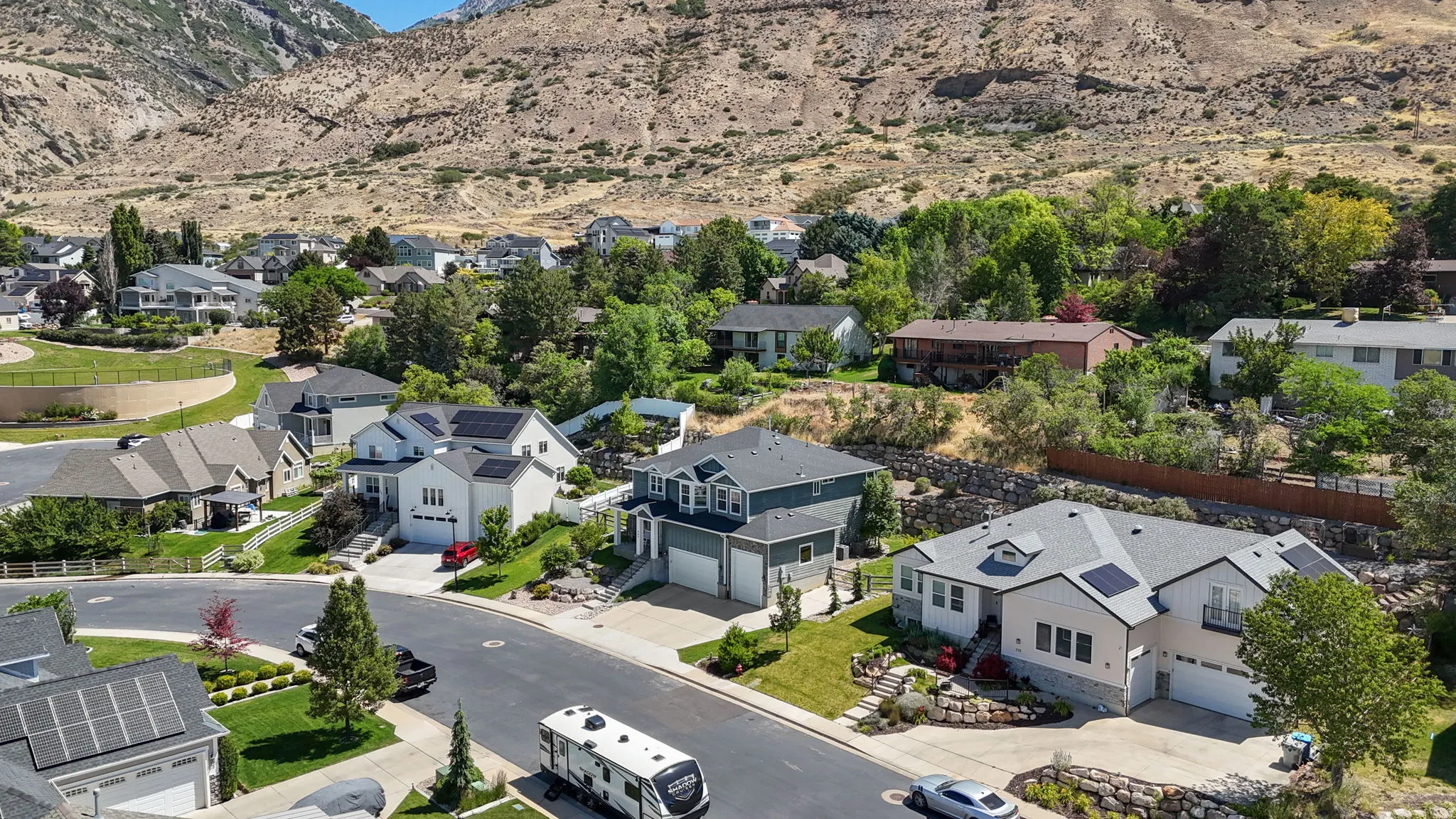 Residential neighborhood featuring homes with dark shingle roofs, solar panels, and attached multi-car garages