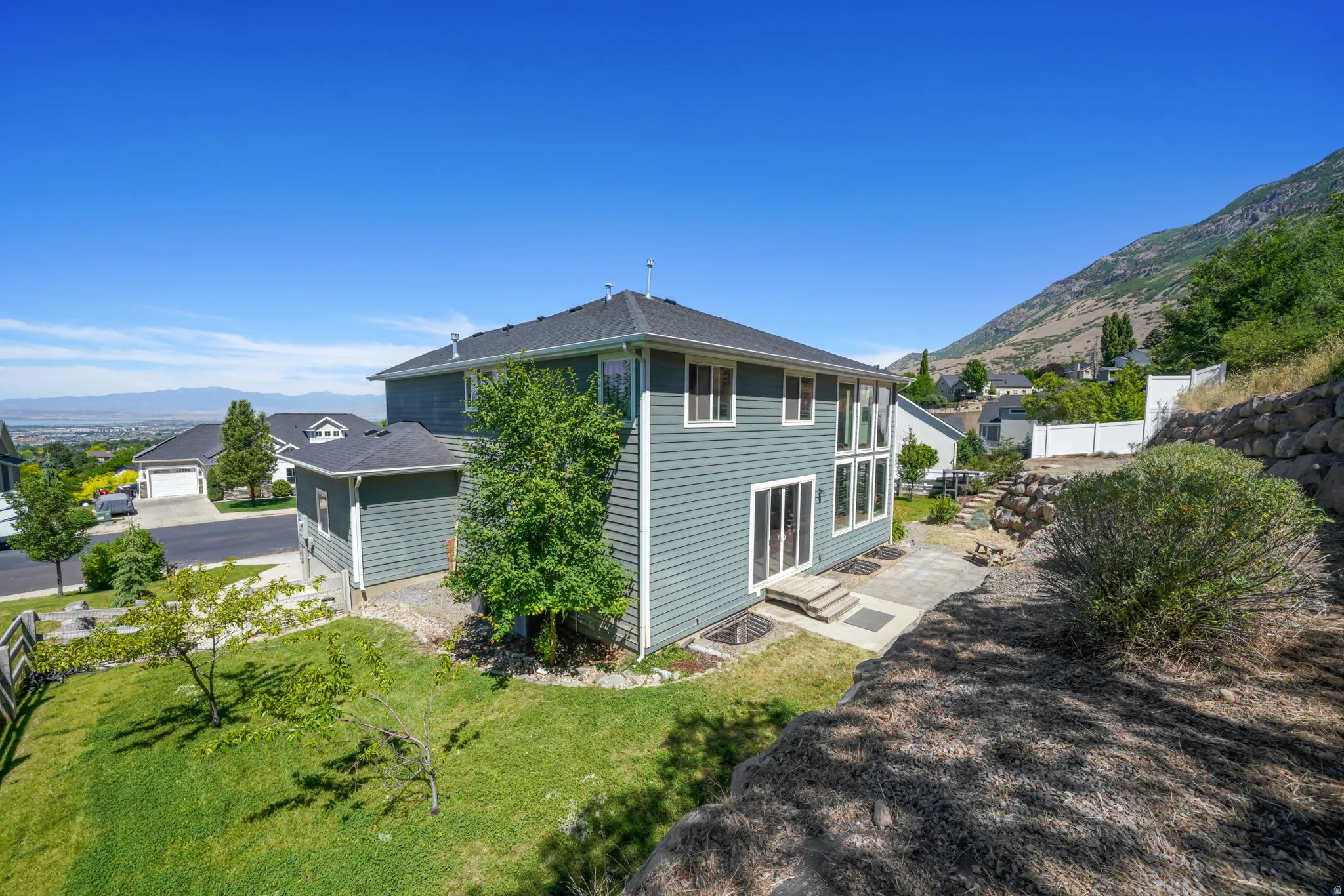 Exterior featuring a multi-level design with siding, a tiered rear patio, and a sloped, landscaped yard