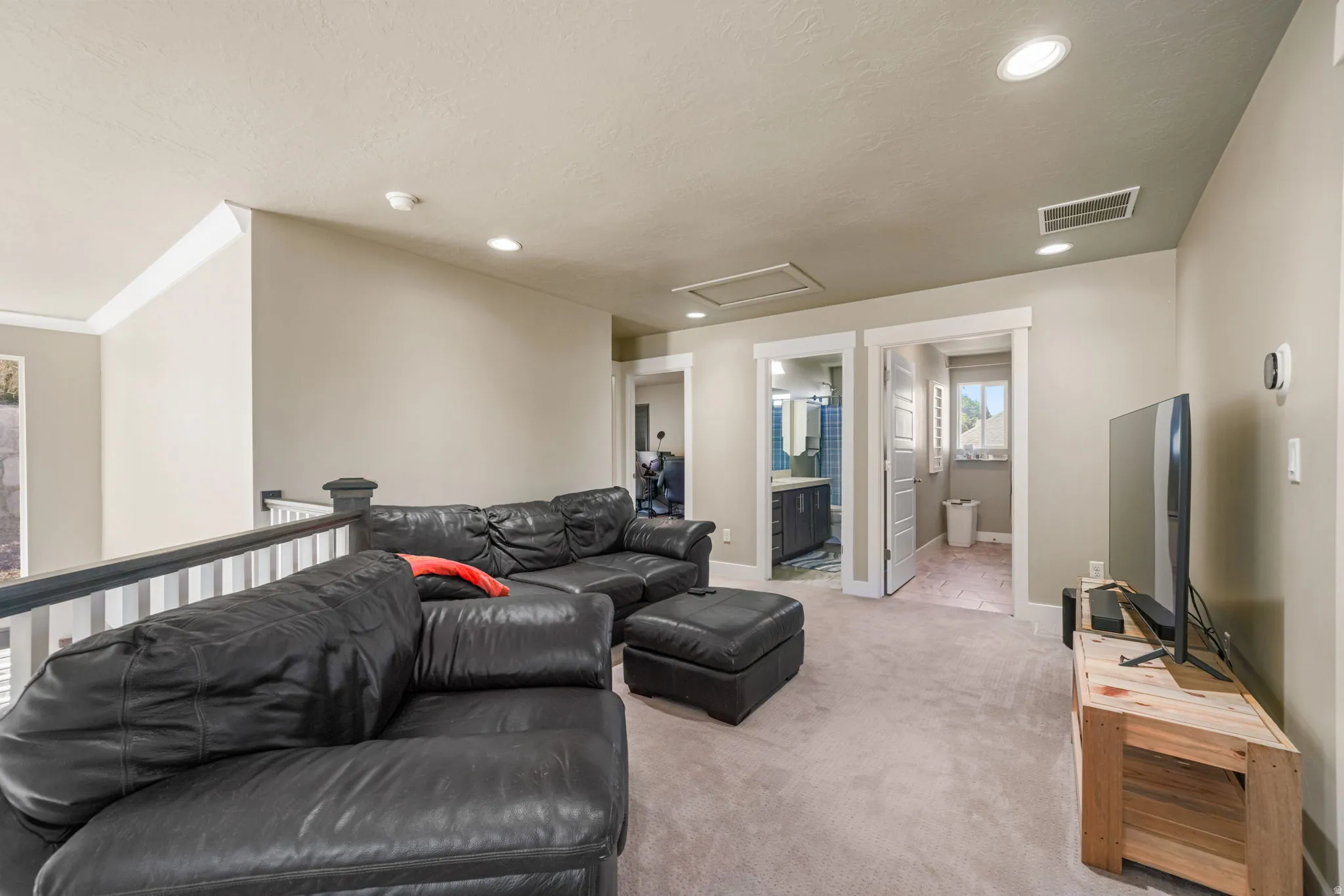 Carpeted loft area with recessed lighting, white baluster railing, and two visible doorways
