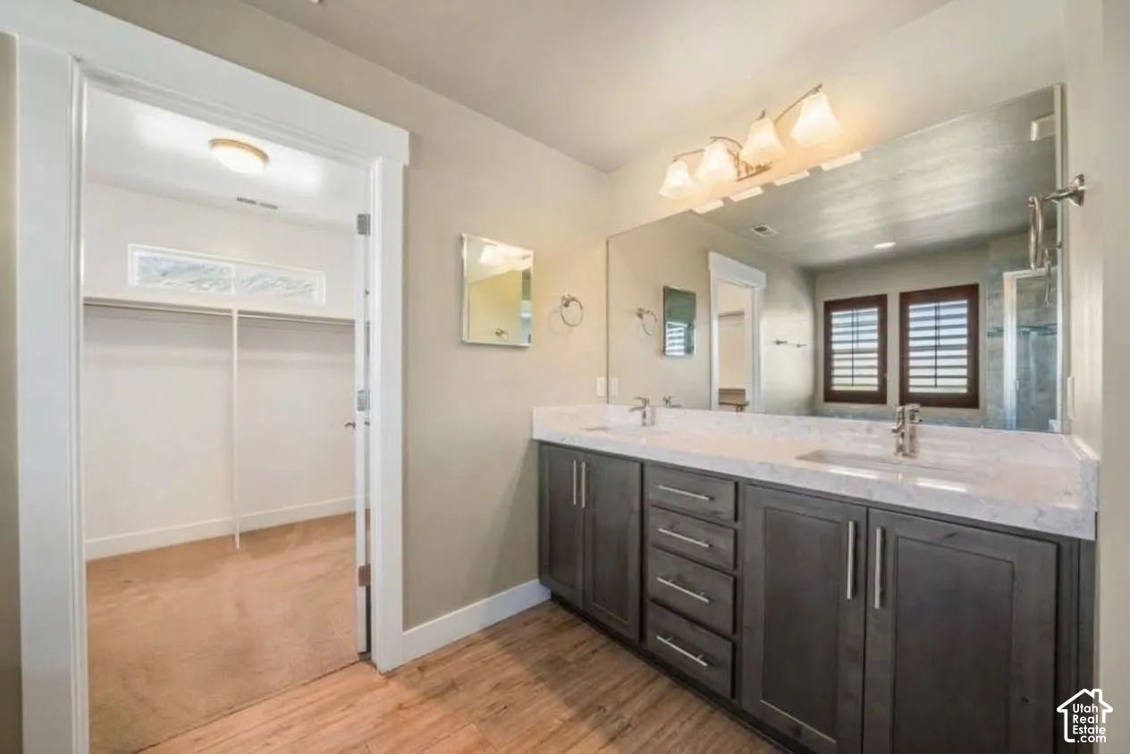 Double vanity with dual sinks, a large mirror, and overhead lighting