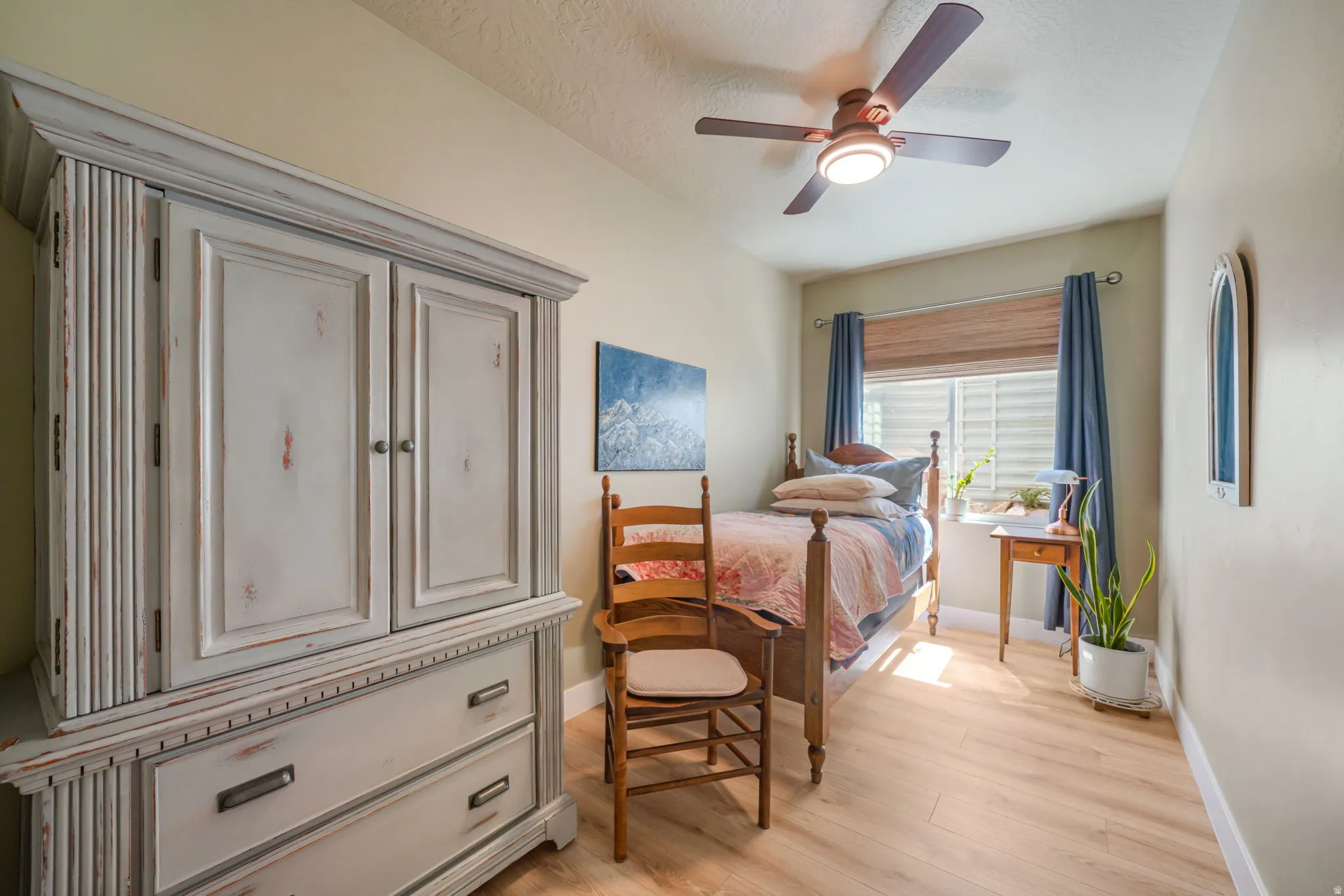 Room featuring wood-finish flooring, a ceiling fan with integrated lighting, and a window with blinds