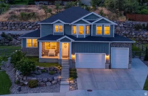Two-story residence featuring a covered front porch, stone accents, and a two-car garage