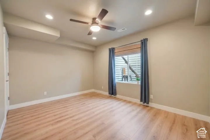 Wood-finish flooring, recessed lighting, ceiling fan, neutral wall paint, and white trim