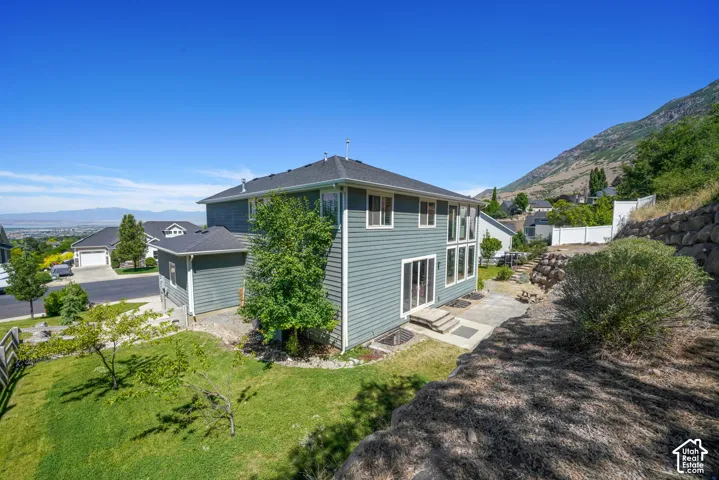 Exterior featuring a multi-level design with siding, a tiered rear patio, and a sloped, landscaped yard