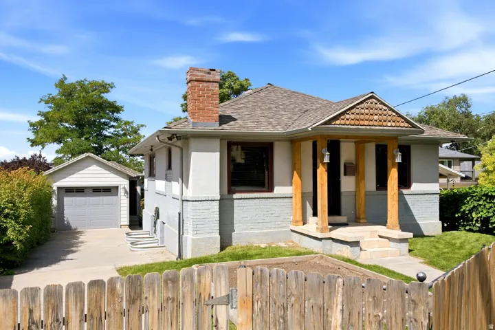 Craftsman-style home featuring a brick chimney, covered front porch with wood-clad pillars, and a detached single-car garage