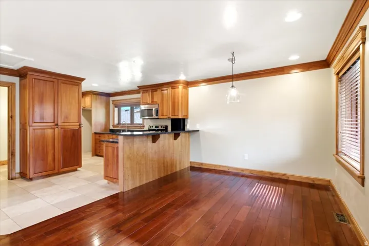 Kitchen and dining area featuring wood-finish flooring, light tone wall paint, wood cabinetry, built-in stainless steel microwave, and recessed lighting