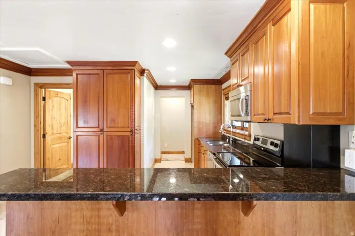 Kitchen featuring a dark granite countertop island with wood-finish base, complementing the wood-finish cabinetry and crown molding
