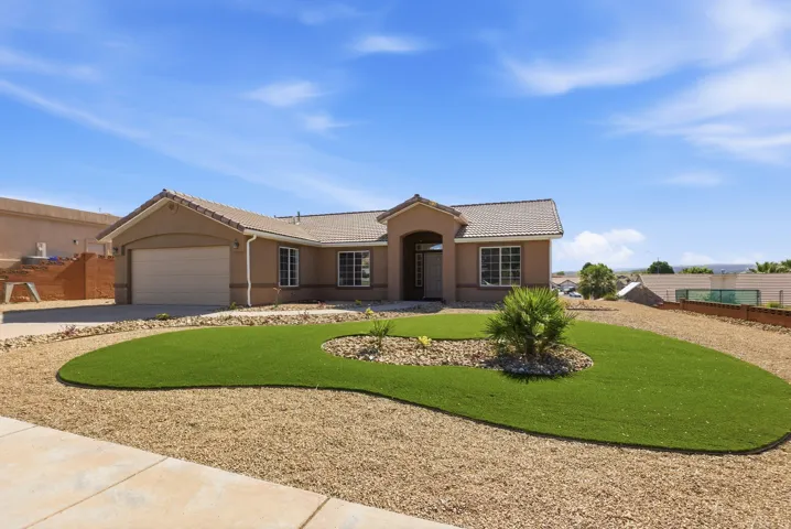 Single-story residence featuring a tan stucco exterior, tile roof, and an attached two-car garage