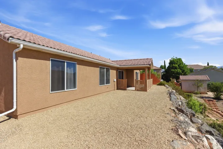 Exterior featuring stucco siding, white window frames, a tile roof, and a covered patio with wood railings
