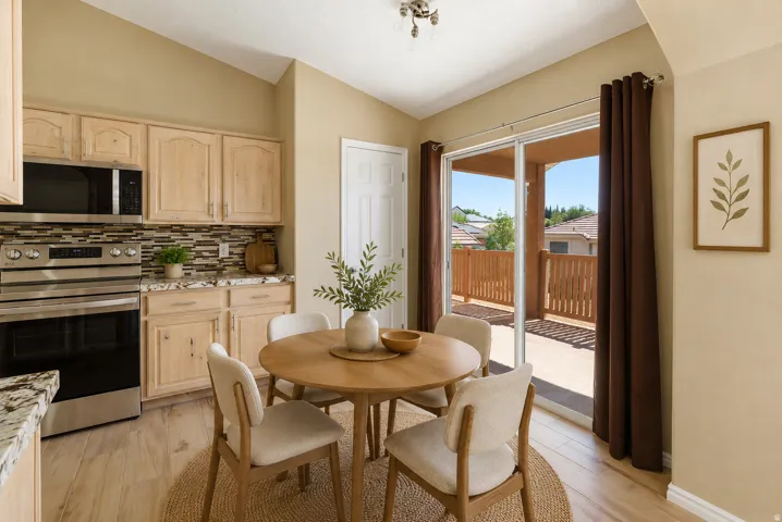 Kitchen dining area featuring wood-finish flooring, wood cabinetry, granite countertops, and a tile backsplash