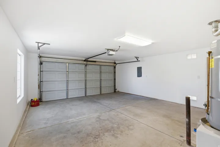 Spacious garage featuring a concrete floor, two windows, two garage doors, and overhead fluorescent lighting