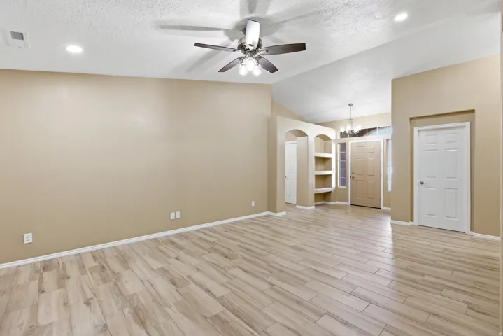 Spacious interior featuring wood-finish tile flooring, vaulted ceilings, and recessed lighting