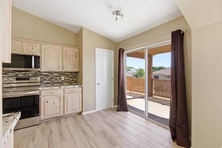 Kitchen featuring light wood cabinetry, stone-finish countertops, and a mosaic tile backsplash