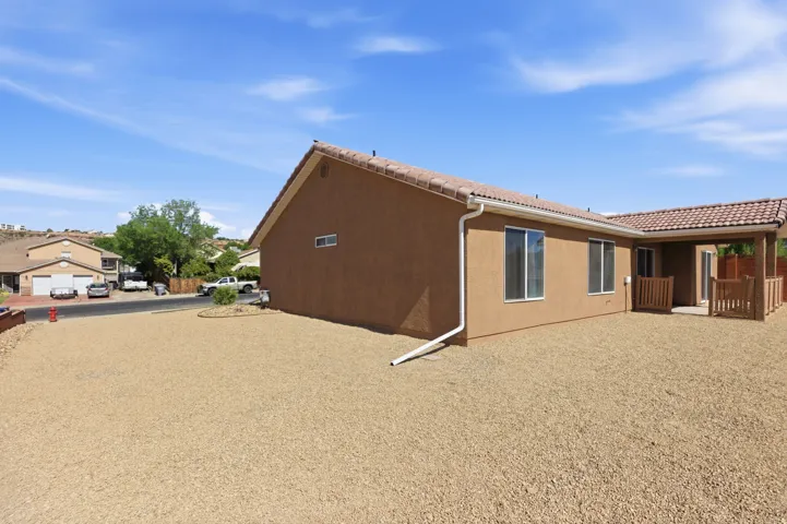Stucco exterior with a tile roof, featuring multiple windows and a covered patio