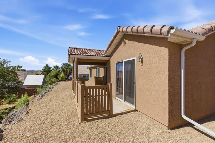 Exterior stucco siding with a tile roof and white rain gutters