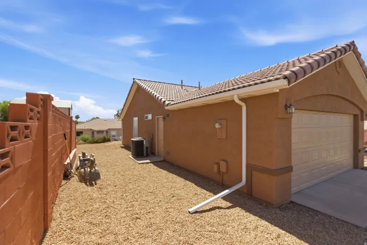 Tan stucco exterior featuring a tile roof and an attached garage with a panel door
