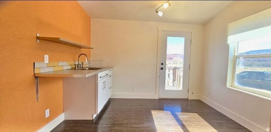 Compact kitchen area featuring a stainless steel sink, a contemporary faucet, and white cabinetry