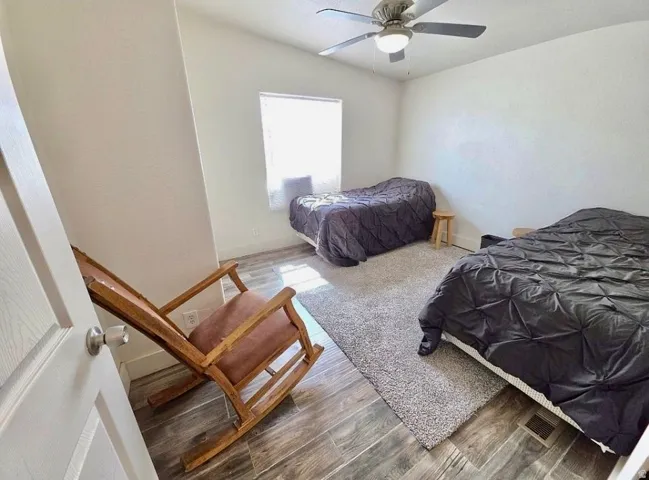 Bright room with wood-finish flooring and a central ceiling fan