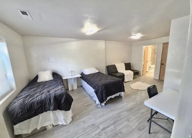 Spacious room featuring light wood-finish flooring, recessed lighting, and a window with blinds