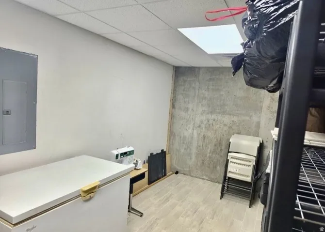 Utility room featuring a drop ceiling, light-toned walls, and wood-finish flooring