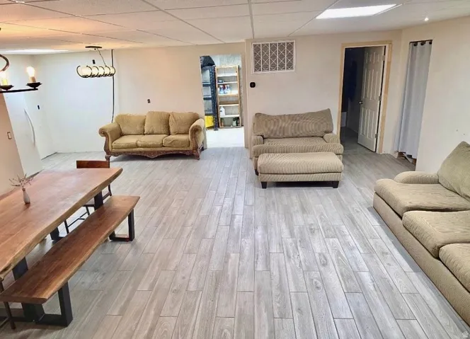 Spacious room featuring wood-finish flooring, a contemporary linear chandelier, and recessed lighting