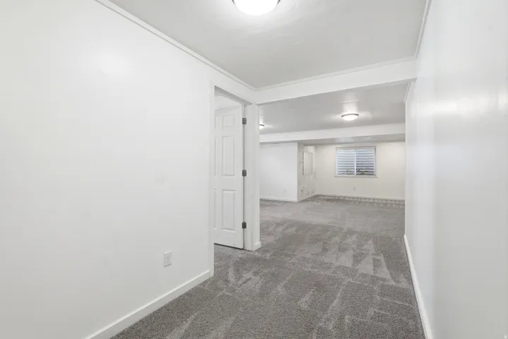 Spacious room with gray patterned carpeting, white painted walls, and white baseboards