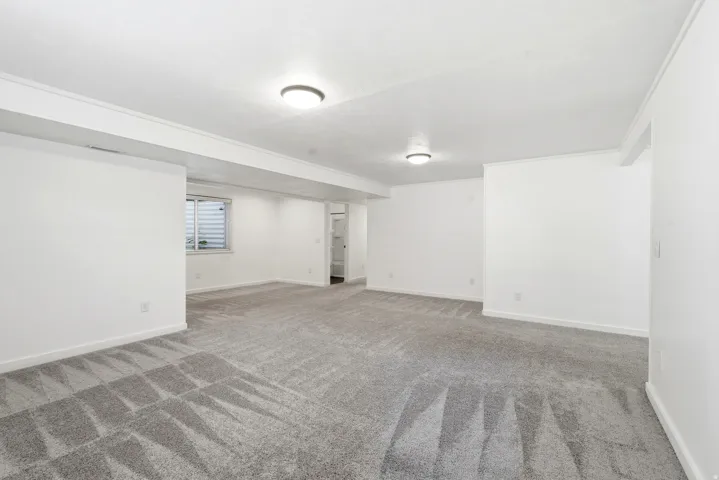 Spacious room featuring neutral carpeting, white walls, and recessed lighting