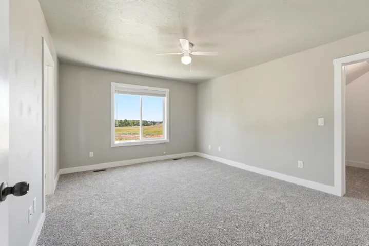 Spacious room featuring neutral carpeting, light gray walls, a white trim package, and a window with a white frame