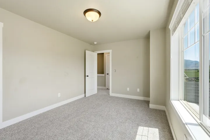 Carpeted interior space with a window offering a distant mountain landscape
