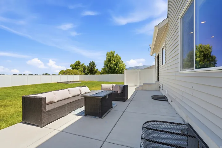 Expansive concrete patio offering a private outdoor area with a large grassy lawn and white privacy fencing